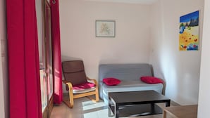 A room with a sofa, a chair, a table, and a painting on the wall. - Charming little cottage in an exceptional Holiday Resort **** in Dordogne-Lot (Gavaudun)