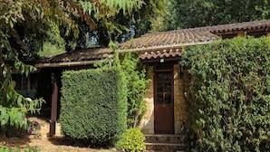 A rustic building with a tiled roof, a wooden door, and a gravel path leading to it. - Charming little cottage in an exceptional Holiday Resort **** in Dordogne-Lot (Gavaudun)