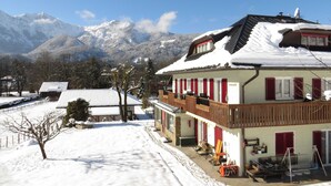 Een met sneeuw bedekte gebouw met balkon, een berg op de achtergrond en heldere lucht.