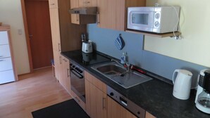 Een kleine keuken met houten kastjes, een magnetron, een broodrooster en een koffiezetapparaat.