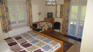 Een slaapkamer met een bed, een bureau, een televisie en een stoel.