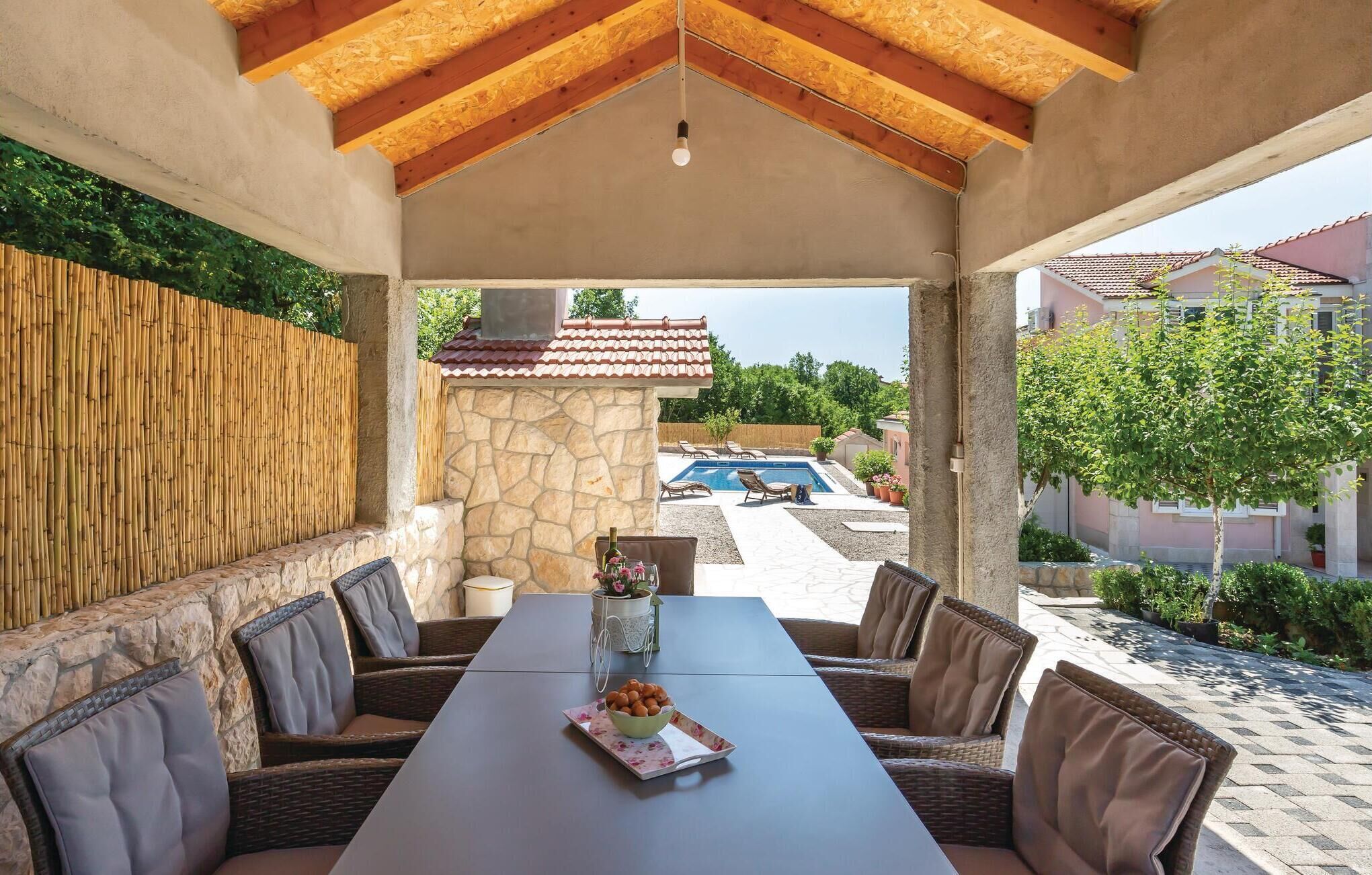 An outdoor patio with a stone wall, a pool, and a view of the neighborhood.