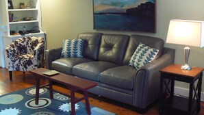 A living room with a leather sofa, patterned armchair, and a small table.