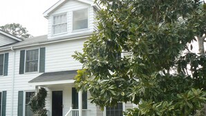 A two-story white house with a front porch, green shutters, and a well-maintained lawn.