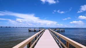 Eine Holzstege, der sich ins ruhige Wasser erstreckt, mit einem wolkenlosen Himmel darüber.