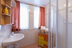 Ein Badezimmer mit Waschbecken, Spiegel und Duschkabine aus Glas.