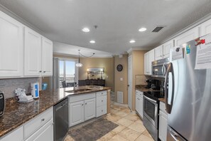 A modern kitchen with white cabinets, stainless steel appliances, and a granite countertop.