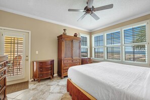 A bedroom with a bed, wooden dresser, and a ceiling fan.