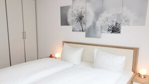 Una cama bien tendida con ropa blanca y dos mesitas de noche con lámparas.
