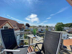 Varanda com vista para casas vizinhas e céu limpo.