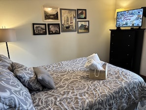 Une chambre d’hôtel avec un lit, des oreillers, une télévision et des tableaux accrochés au mur.