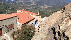 A mountainous landscape with a view of the sea, a building with a red-tiled roof, and a rocky cliff. - CORSE HOUSE EXCEPTIONAL SEA VIEW IN A VILLAGE BETWEEN SEA & MOUNTAINS (Speloncato)