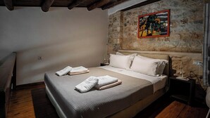 A bedroom with a large bed, a stone wall, and a painting. - Villa complex nearby Rethymno with stunning countryside views! (Rethymno)