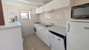 A compact kitchen with white cabinets, a built-in dishwasher, a stove, and a microwave. - Charming family cottage in Holiday Resort **** swimming pool, tennis, bar, etc. (Gavaudun)