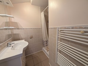 Ein Badezimmer mit einem weißen Waschbecken, einer Duschkabine und einem weißen Handtuchhalter.