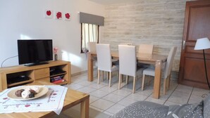 Un salon équipé d’un téléviseur, de meubles en bois, d’une table à manger et d’un canapé.