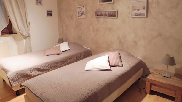 Une chambre d’hôtel avec deux lits, une table de chevet en bois, une lampe et un mur orné de tableaux.