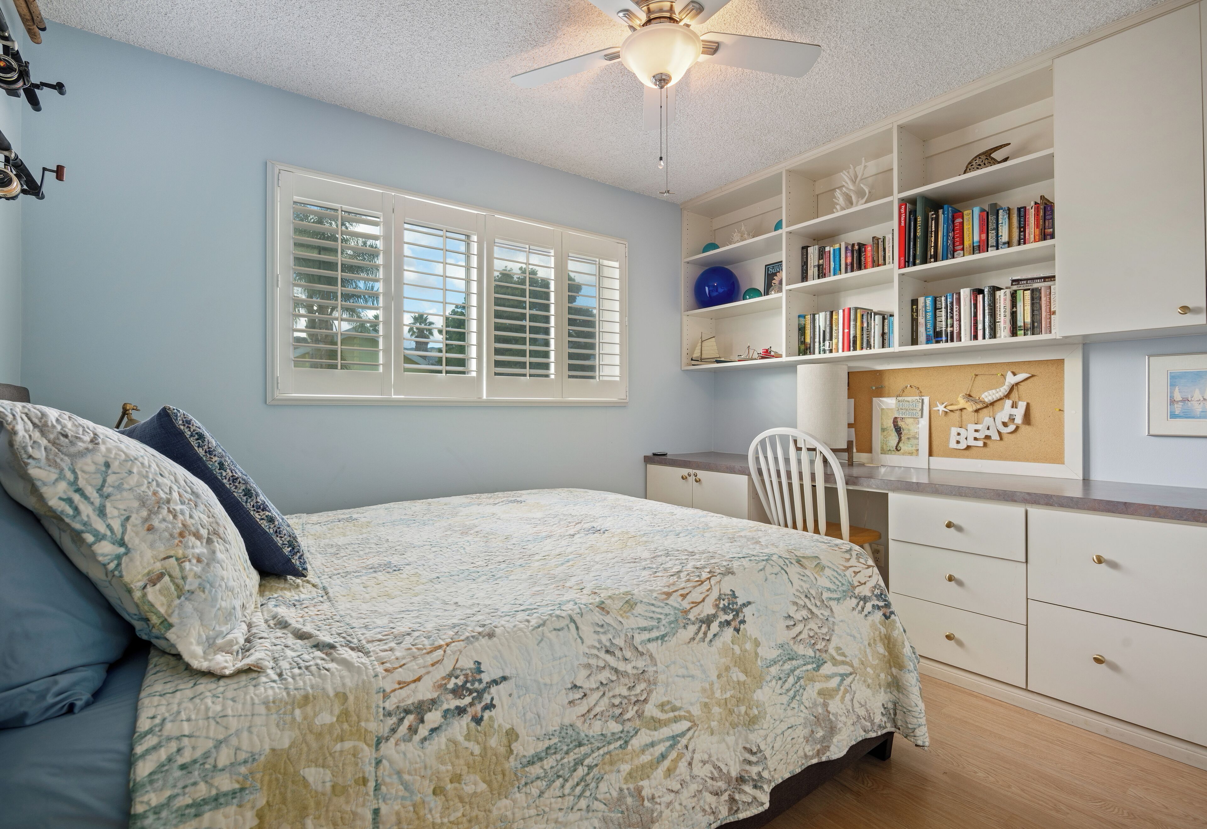 A bedroom with a bed, a bookshelf, a desk, and a chair.