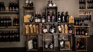 A wine shop with various bottles and boxes of wine on wooden shelves and crates. - Weinbar und Hotel FahrAway (Volkach)