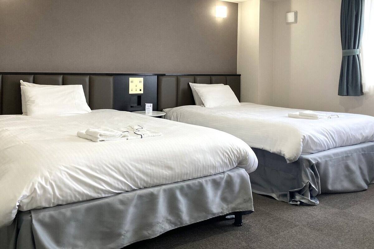 Two single beds with grey headboards and white bedding in a hotel room.