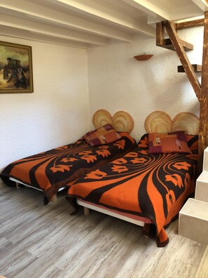 A room with two beds, a wooden staircase, and a painting on the wall.