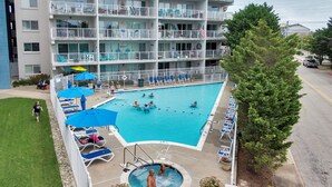 A hotel with a swimming pool, lounge chairs, and a multi-story building. - Bay Front Condo-2br/2ba , Pool, Hot Tub, Lr Balcony W/ Beautiful Sunsets, WIFI.  (Ocean City)