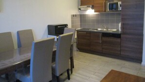 Una cucina compatta con tavolo e sedie, un forno a microonde, un tostapane e pensili.