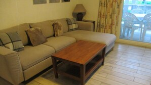 Un soggiorno con un divano beige, un tavolino in legno e una lampada.
