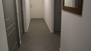 Un corridoio stretto con pavimenti tappezzati, una porta chiusa in fondo e uno specchio sulla parete destra.