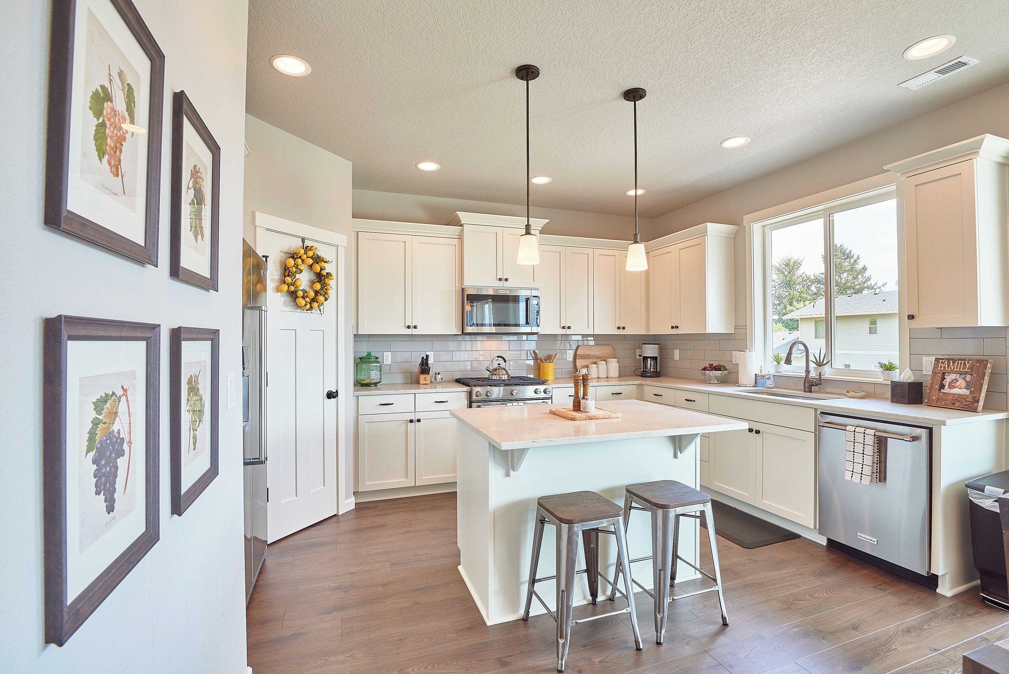 A modern kitchen with white cabinets, stainless steel appliances, and a large island with stools.