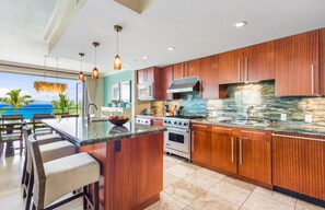 Una cocina moderna con armarios de madera, una isla grande con taburetes de bar, estufa, horno y microondas.