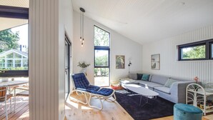 Un salon moderne avec un plancher en bois, un fauteuil bleu, un canapé gris et une table basse noire.