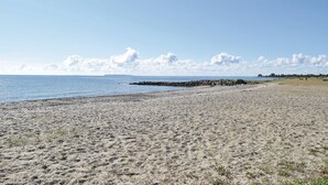 Une plage de sable avec une digue rocheuse et un ciel dégagé.