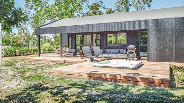 Une terrasse extérieure moderne dotée d’un jacuzzi, d’un espace salon et d’un barbecue.
