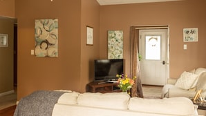 Een woonkamer met een flatscreen televisie, een bank, een salontafel en een deur met een lamp.