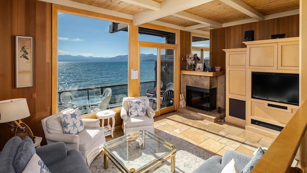 Un salon chaleureux avec des murs et un plafond en bois, une table basse en verre et une vue sur la mer.
