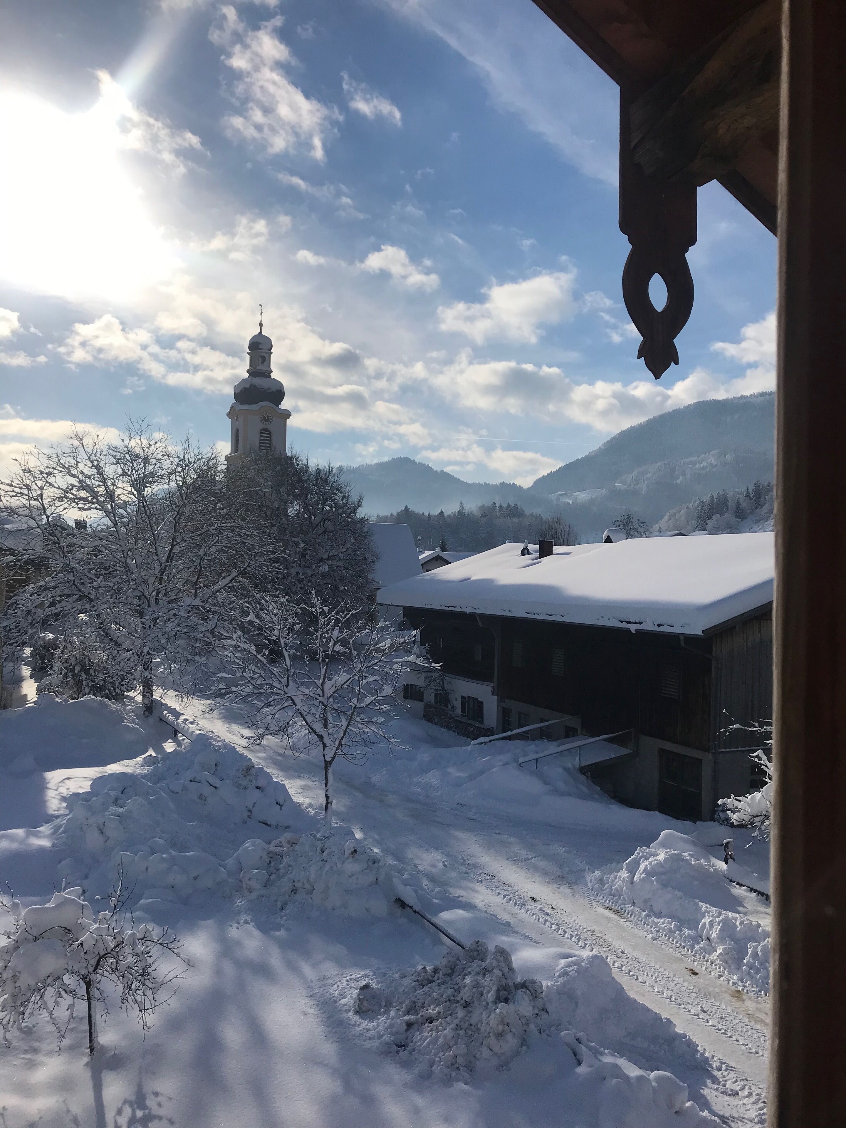 A snow-covered landscape with a church and buildings, a clear sky, and mountains in the background.