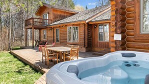 Eine Blockhütte mit Whirlpool, Sitzgelegenheit im Freien und einer Terrasse.