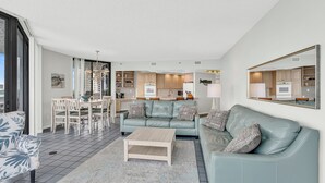 A modern living room with a sofa, coffee table, and dining area. - Free Beach SRVC! Fab Ocean Views! Free Beach Bonfires M/F (Miramar Beach)