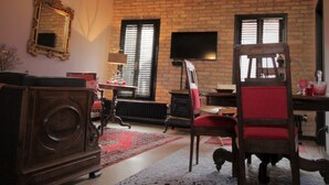 Una sala de estar acogedora con vigas de madera a la vista, una pared de ladrillo, una chimenea y un sillón rojo.