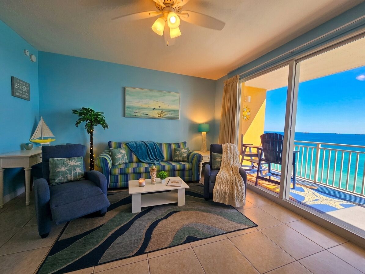 A living room with a sofa, armchairs, a coffee table, and a view of the ocean.