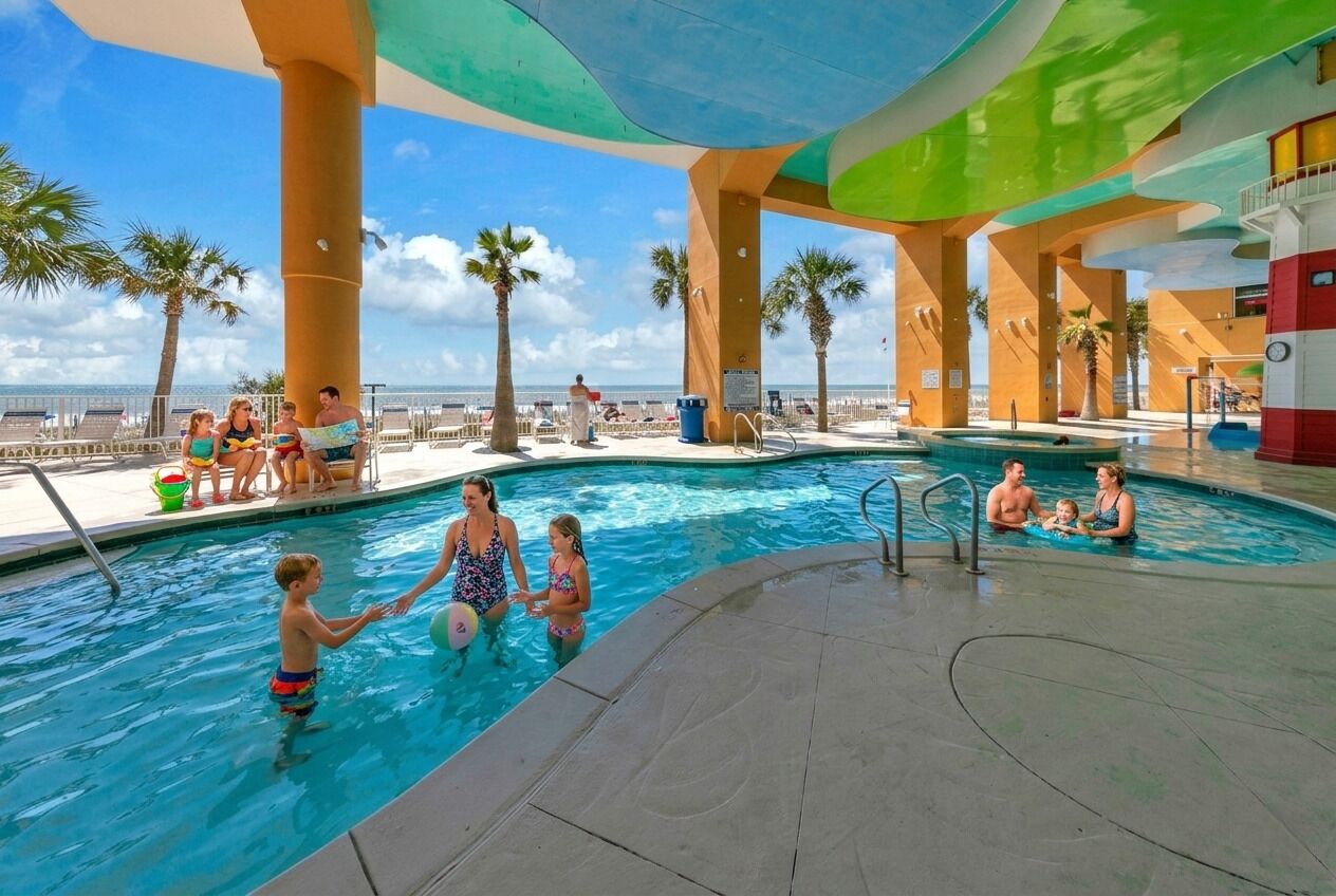 Un espace piscine comprenant plusieurs piscines, des palmiers et une vue sur la plage.