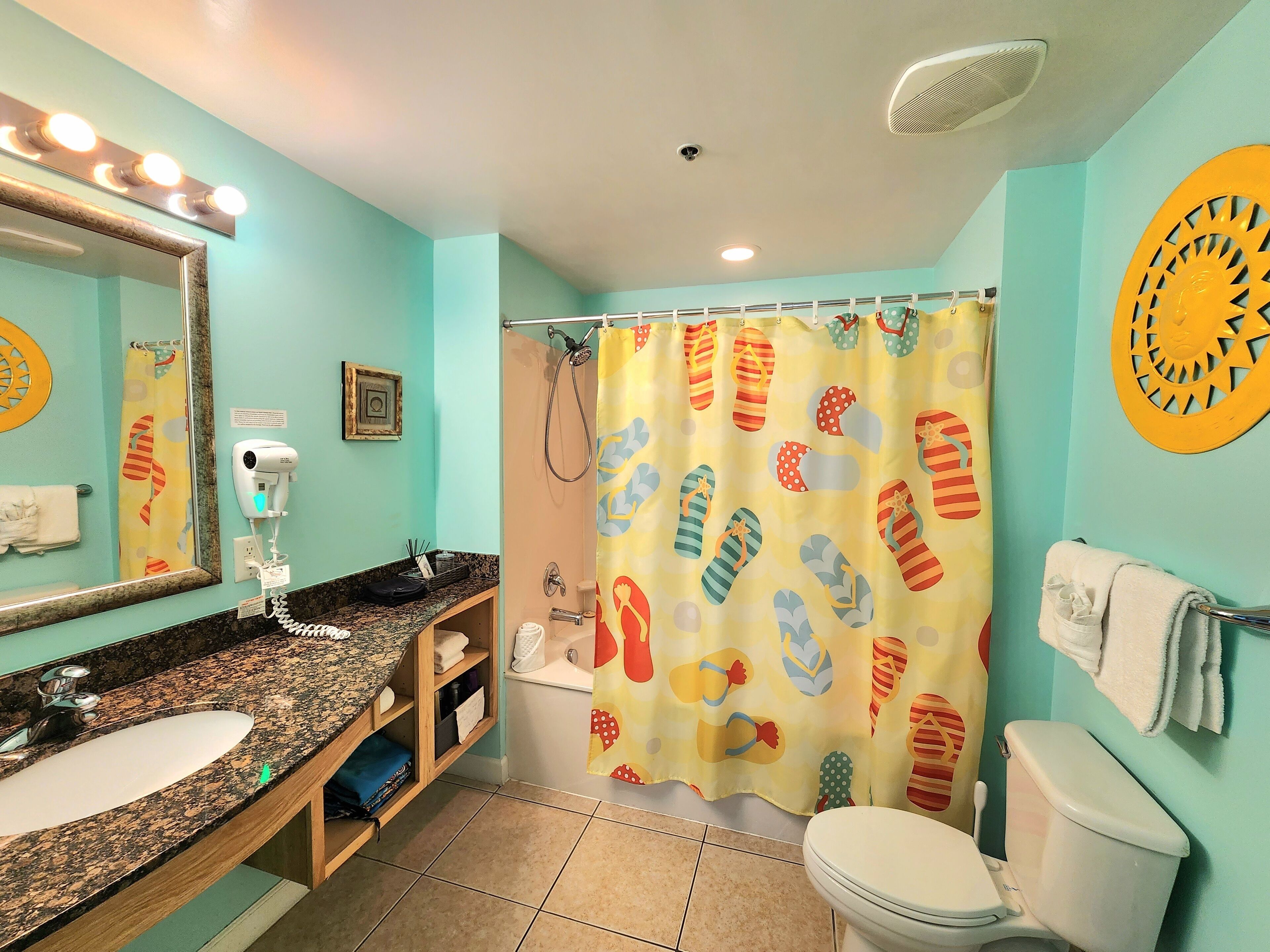 Une salle de bain équipée d’un lavabo, d’un miroir, d’un rideau de douche et de toilettes.