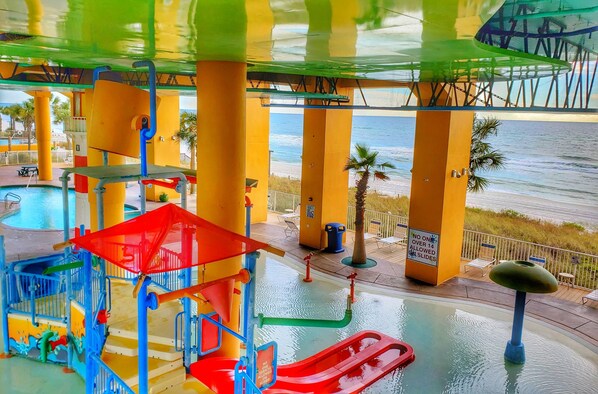 A water park with slides and a pool, overlooking a beach.