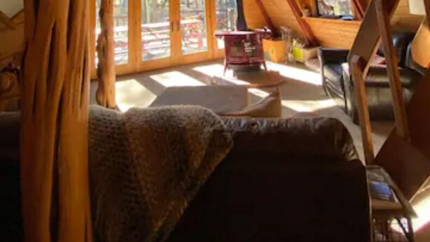 A cozy attic room with a sloped ceiling, a ceiling fan, and a large window allowing natural light. - Stunning OFF-GRID Cabin Retreat! Quiet and Private !!! (Flagstaff)