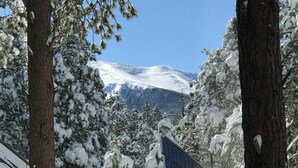 A snowy outdoor area with a wooden deck, snow-covered trees, and a mountain in the background. - Stunning OFF-GRID Cabin Retreat! Quiet and Private !!! (Flagstaff)