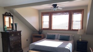 Ein Schlafzimmer mit Bett, Kommode, Nachttisch und Deckenventilator.