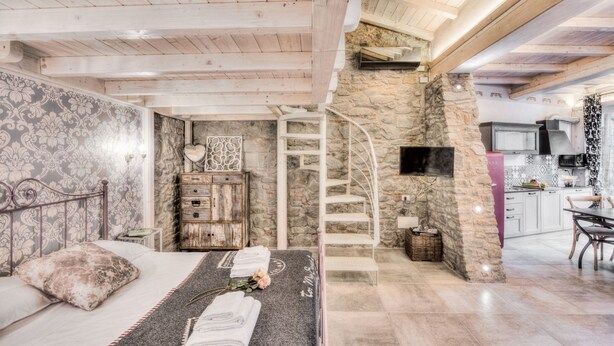 Une chambre comprenant un lit, une commode, une coiffeuse, un escalier et un coin cuisine.