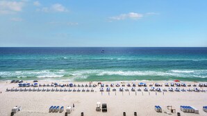 Una spiaggia con file di lettini e ombrelloni, cielo sereno e l'oceano.
