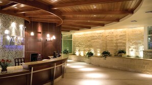Una zona reception con scrivania in legno, una parete a mosaico e una parete in pietra con piante.